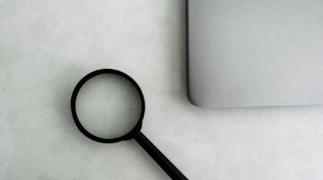 Magnifying glass sits near a laptop on a table.