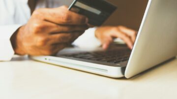 person using laptop computer holding card